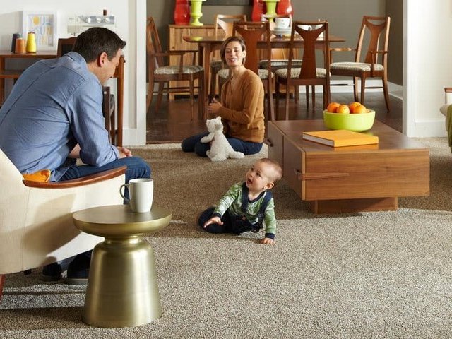 baby playing on carpet with his parents